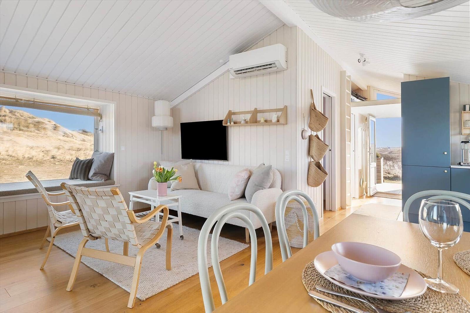 Living and dining area with sofa, chairs, and view of the landscape.