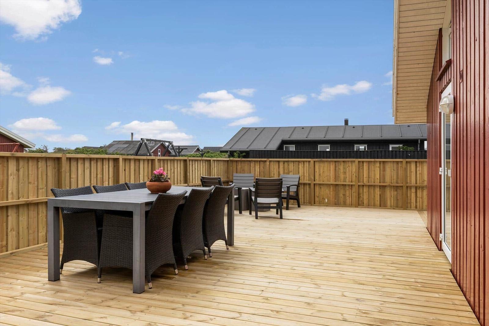 Terrasse mit Holzdecke, Gartenmöbel und Blick auf Nachbarhäuser.