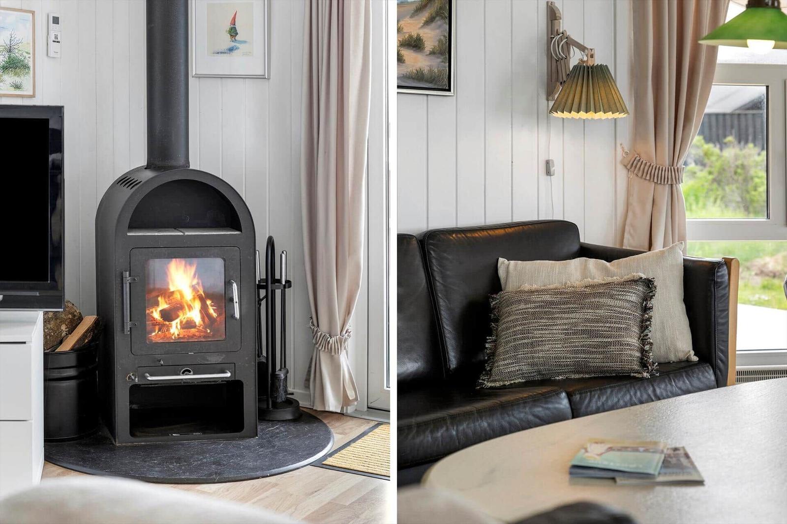 Kamin mit brennendem Holz und schwarzer Ledercouch mit Kissen.