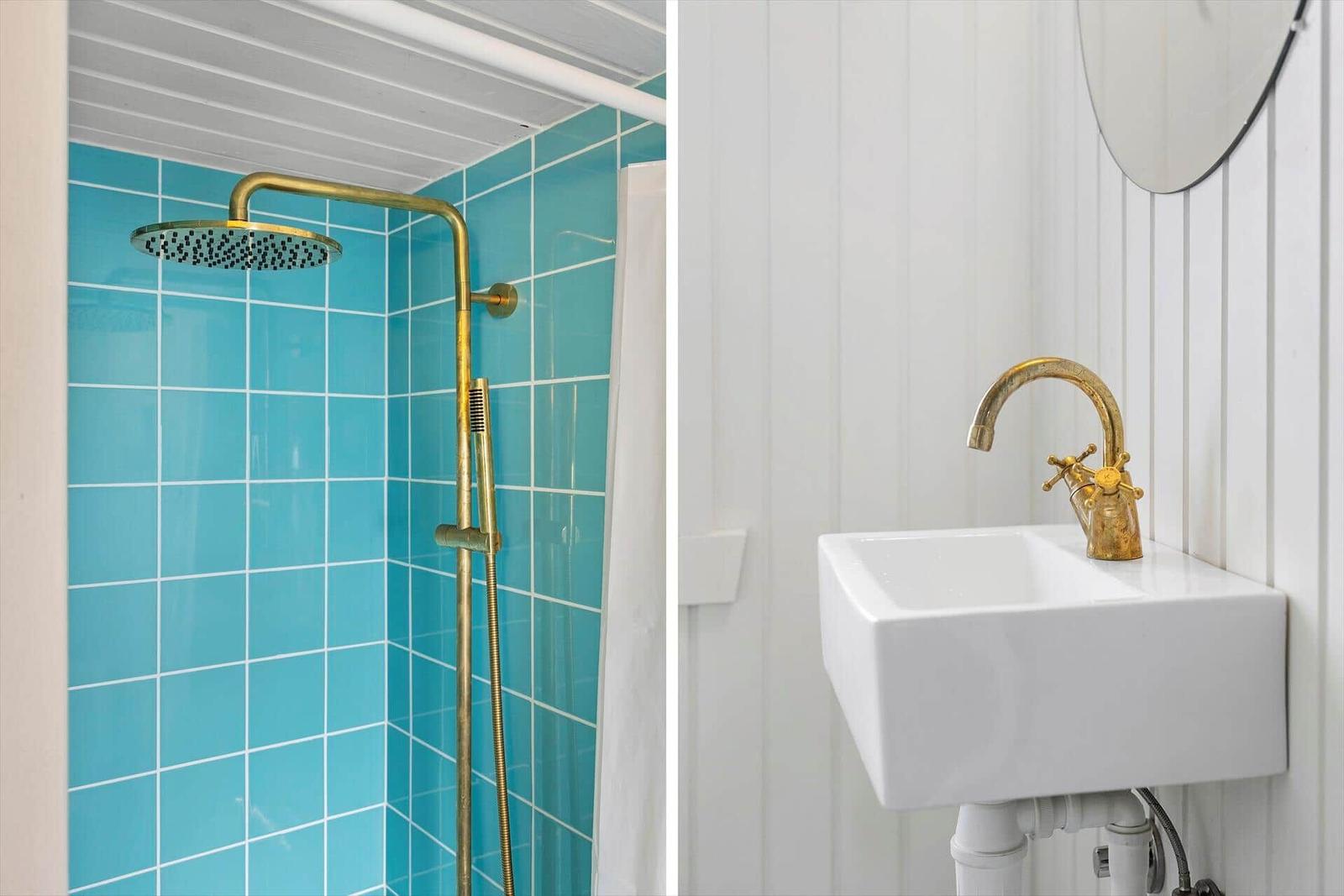 Bath with blue tiles and gold shower system. Toilet and sink with gold faucet.