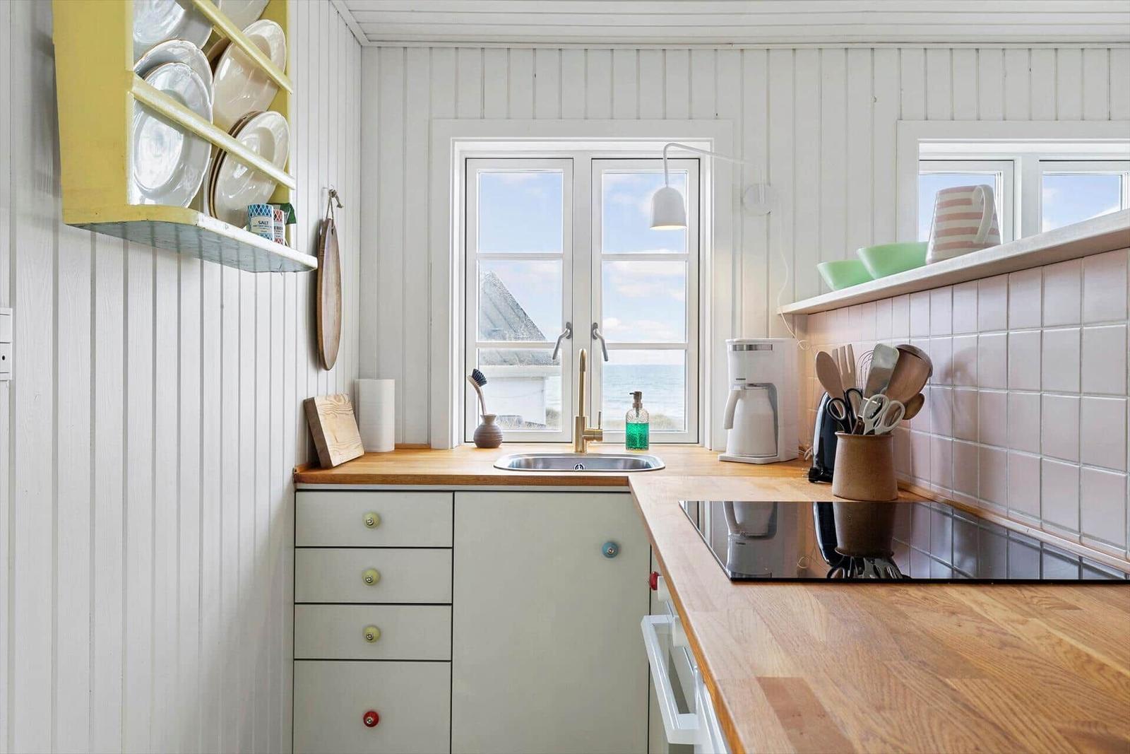 Kitchen with wooden surfaces, sea view window, and kitchen appliances.