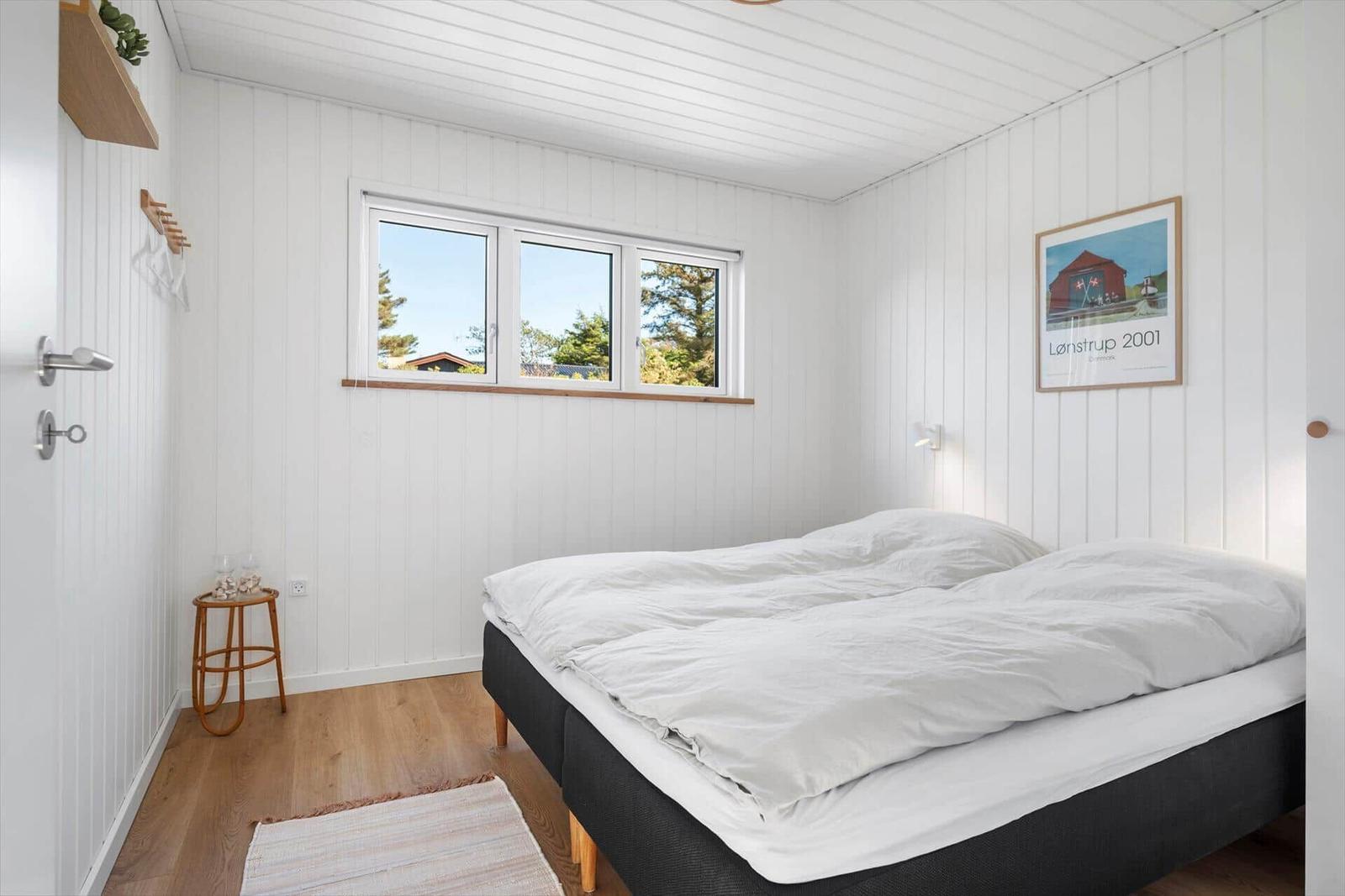 Schlafzimmer mit Doppelbett, Fenster und Wandbild.