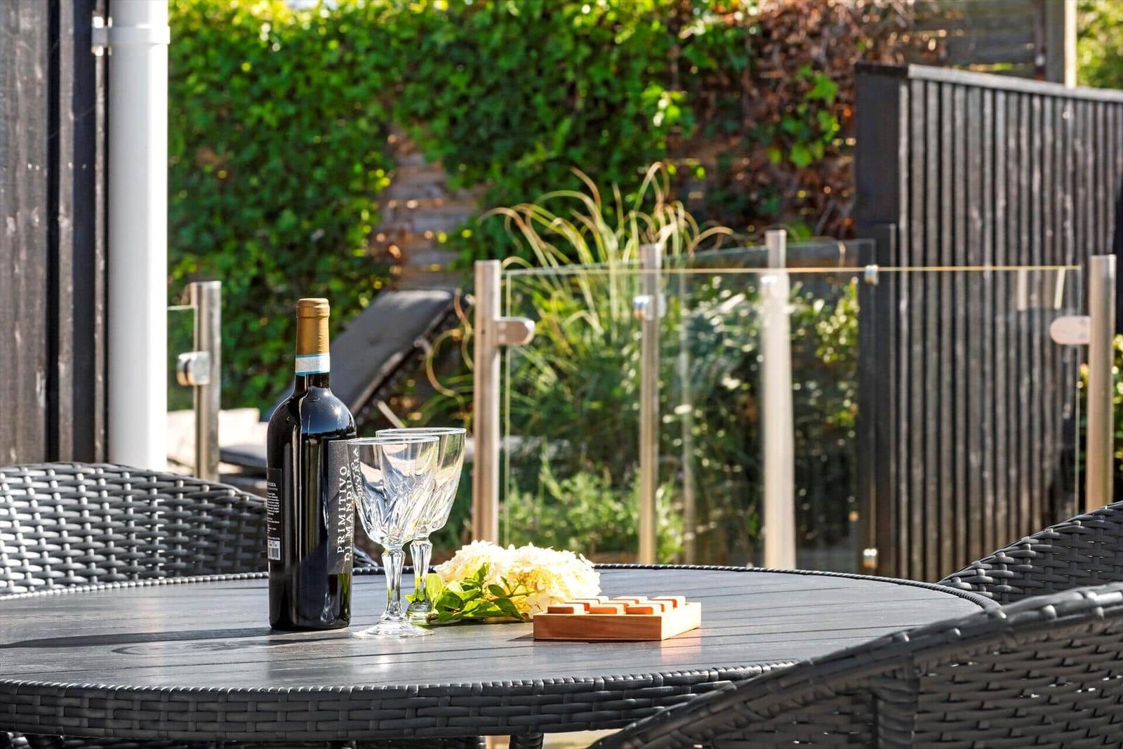 Runder Tisch mit Weinflasche, Gläsern und Blumen im Garten