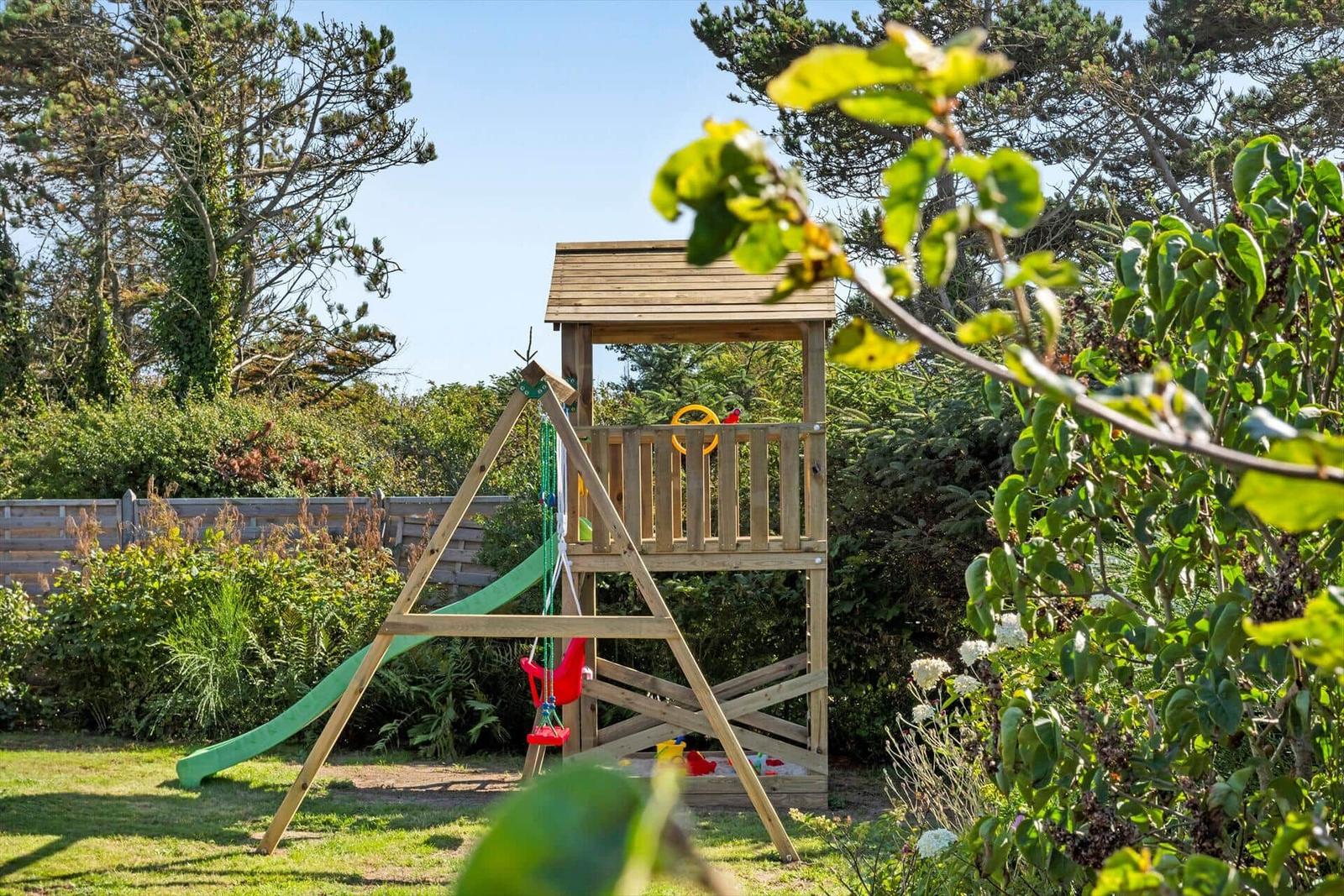 Holzspielplatz mit Rutsche und Schaukel im Garten