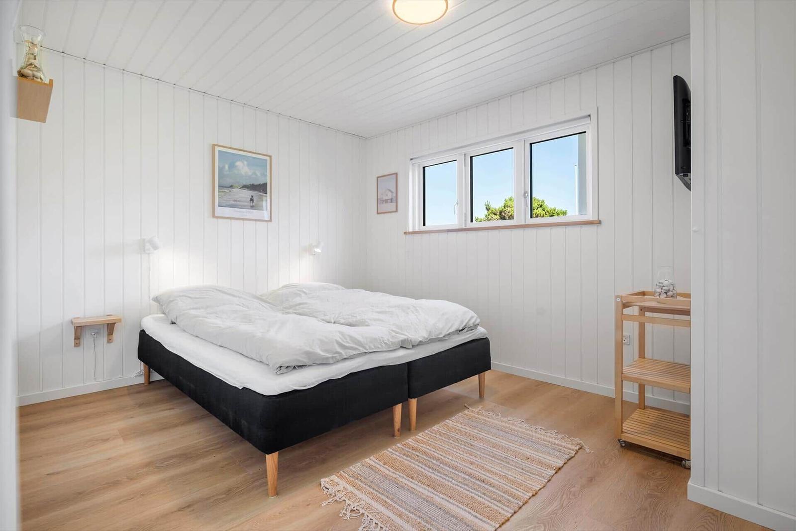 Schlafzimmer mit Doppelbett, Fenster und Holzboden.