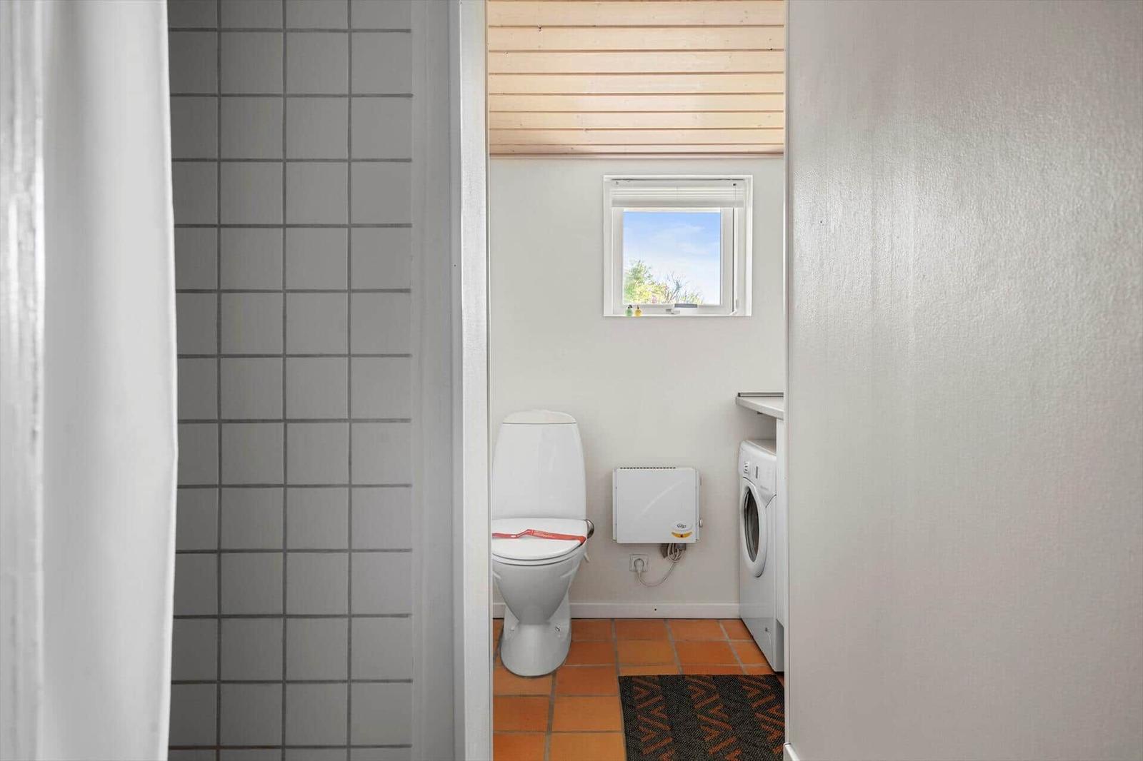 Badezimmer mit Toilette, Waschmaschine und Fenster
