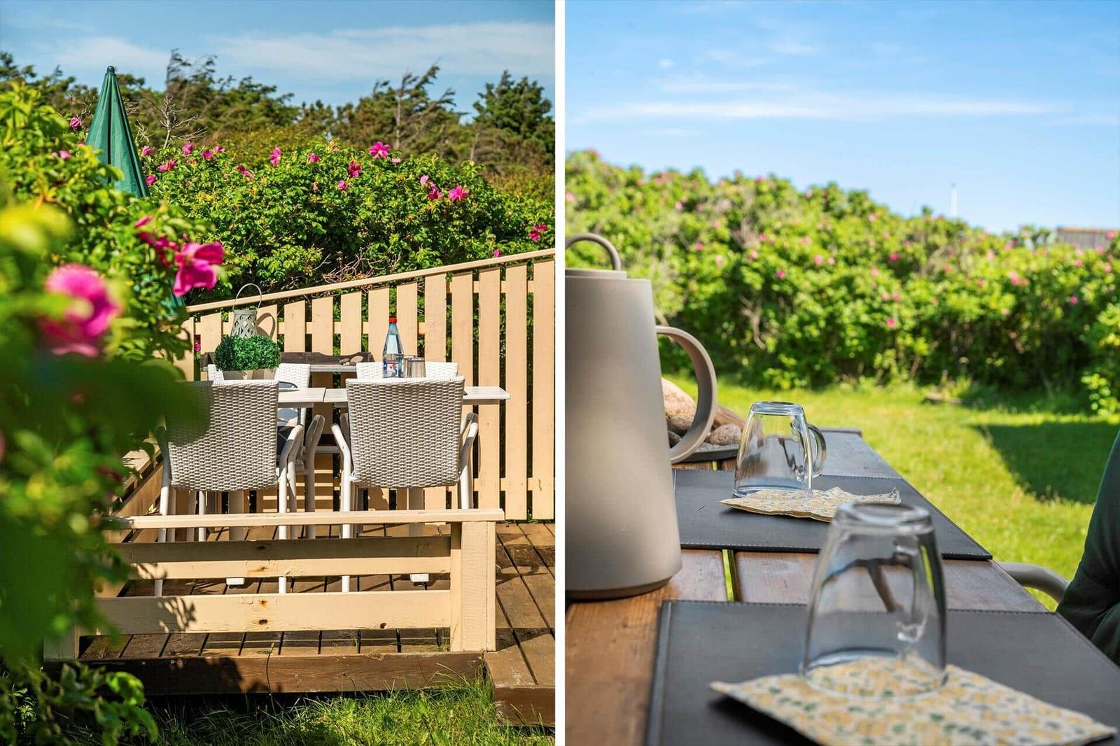 Terrasse mit Tisch und Stühlen, umgeben von grünen Pflanzen und rosa Blüten.