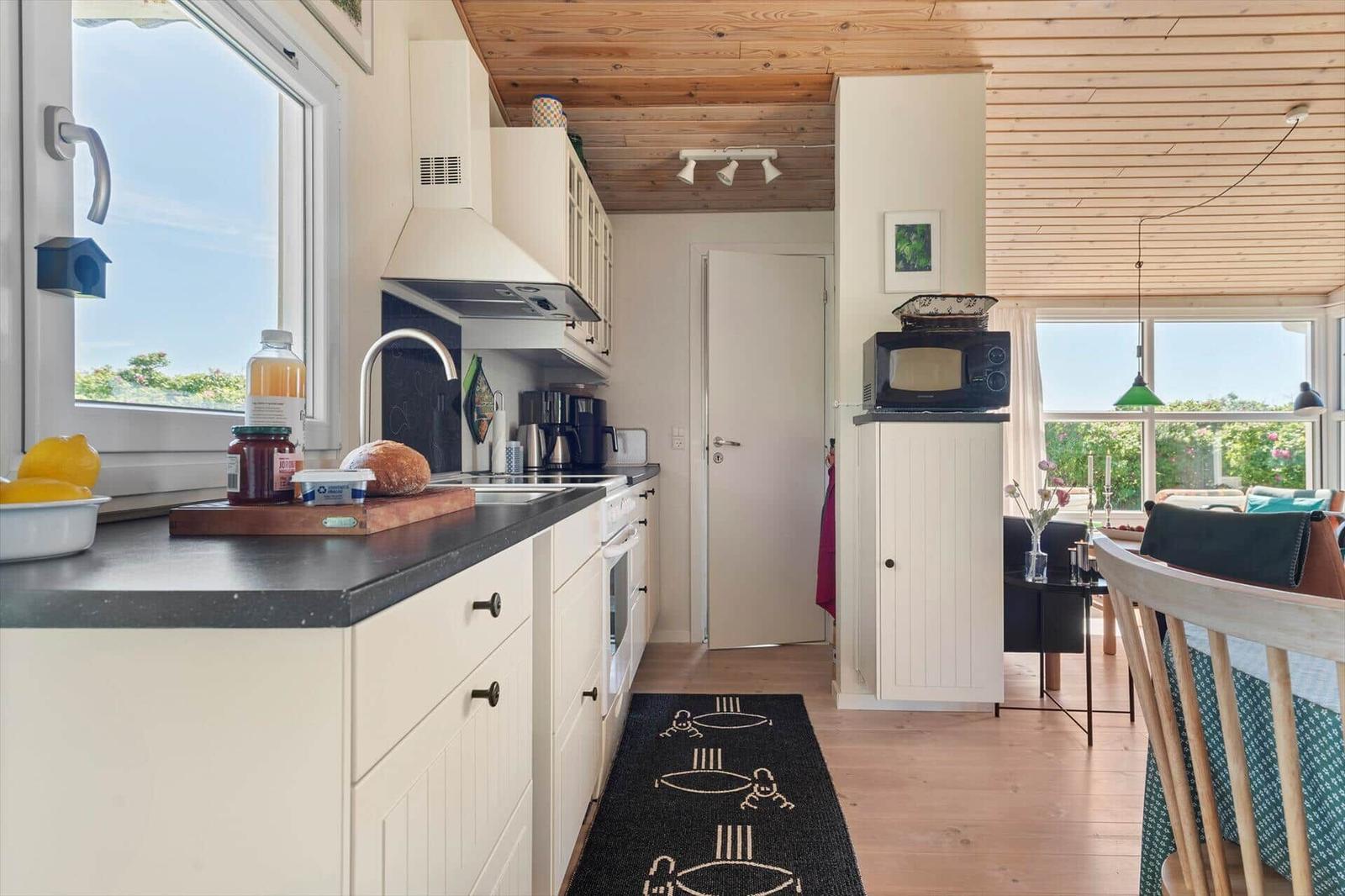 Küche mit Arbeitsplatte, Fenster und Blick ins Wohnzimmer.