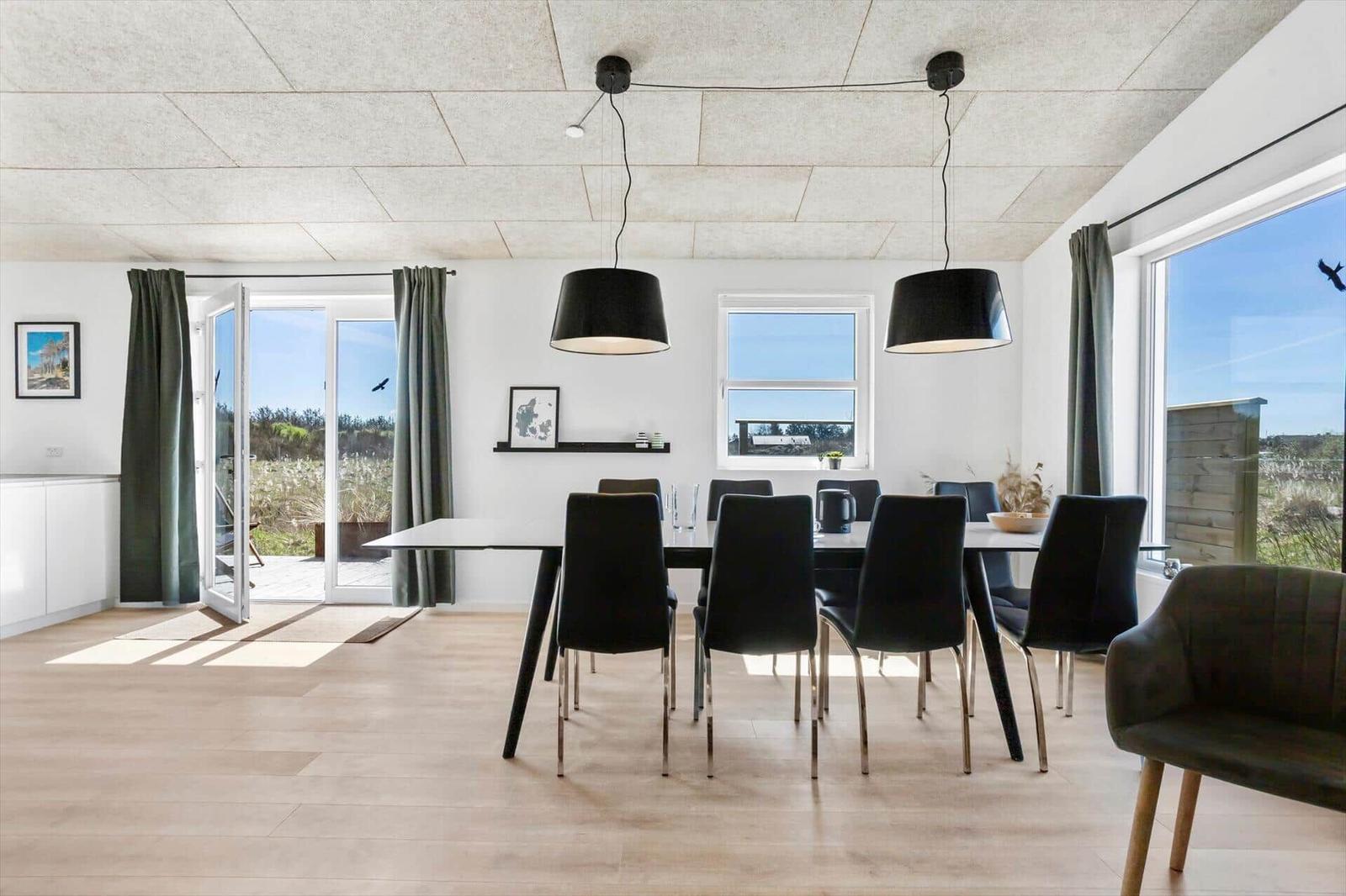 Dining room with table, chairs, and large windows offering outdoor views.