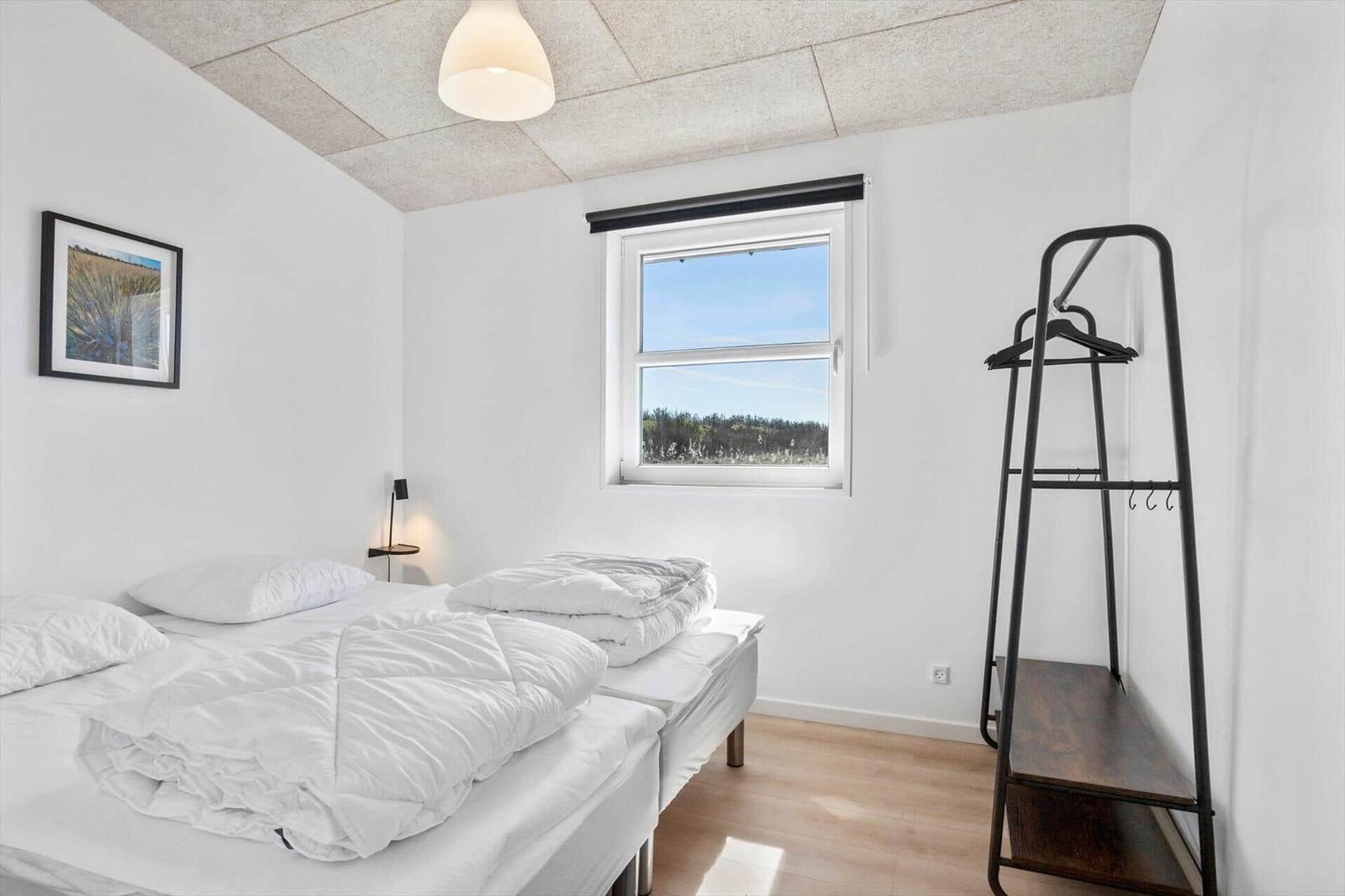 Room with double bed, window, and coat rack