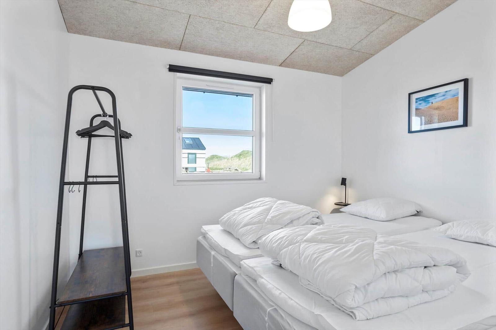 Bedroom with double bed, clothing rack, and window overlooking green areas.