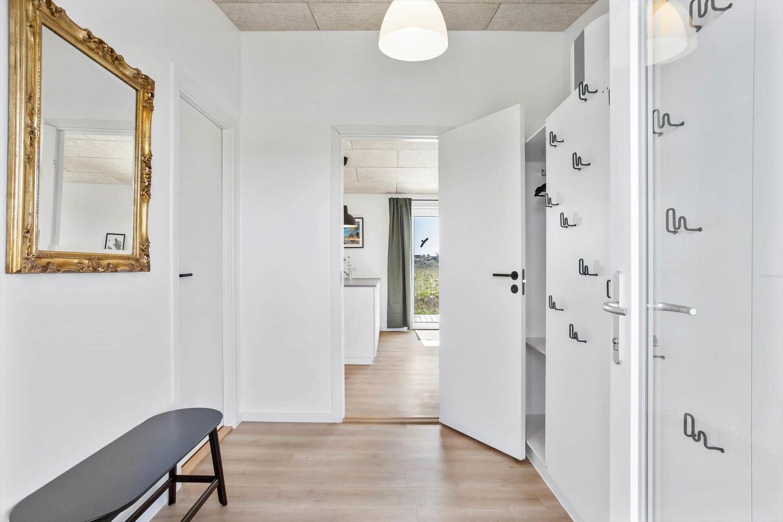 Hallway with mirror, bench, and closet. Corridor to kitchen and terrace.