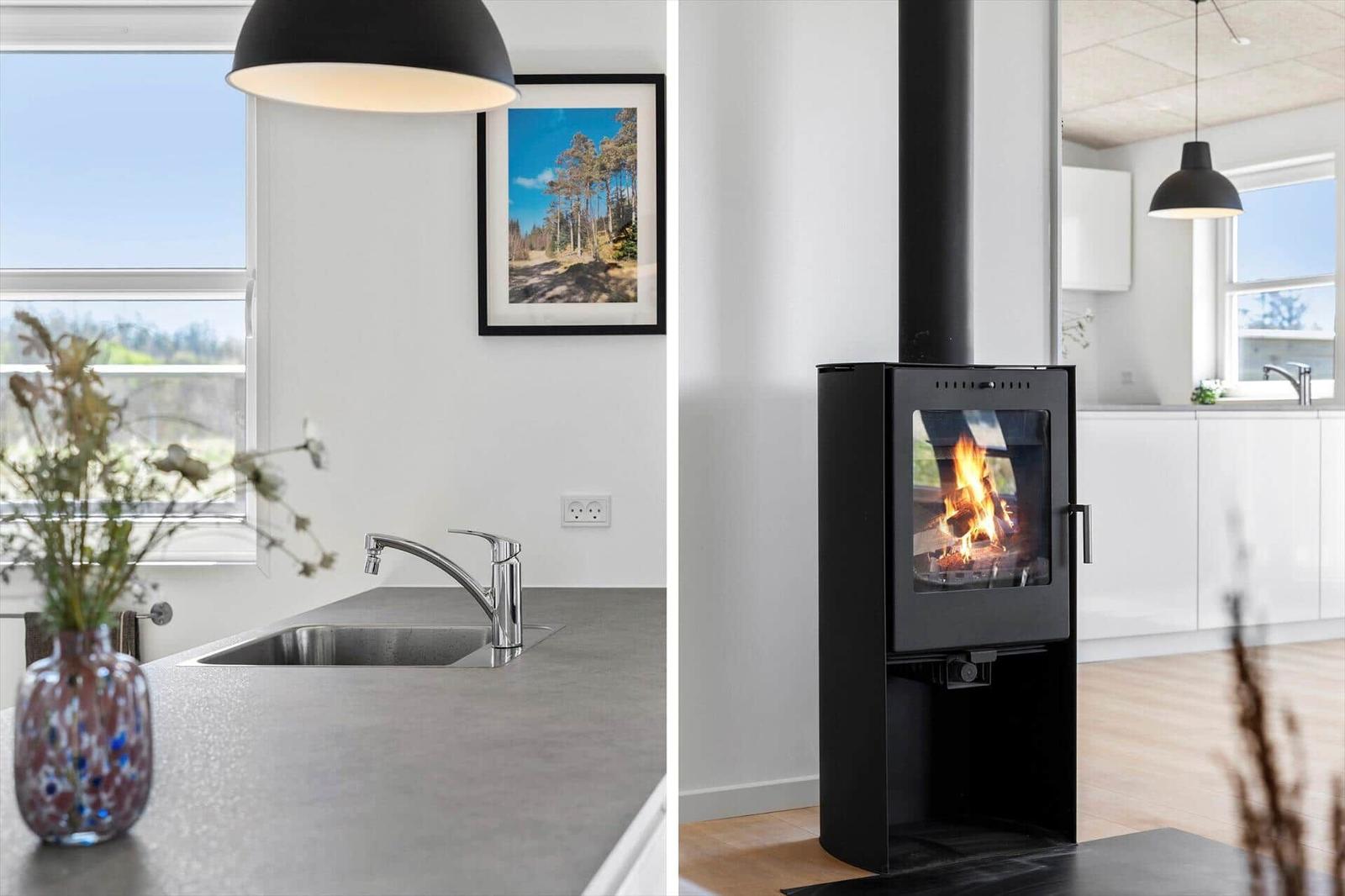 Kitchen with window and sink. Wood-burning stove with fire.