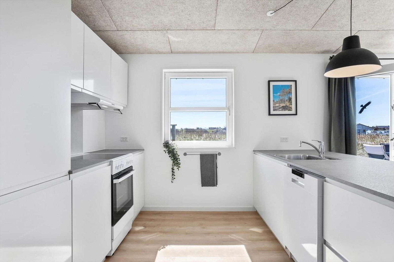Modern kitchen with white cabinets, countertop, and window view.