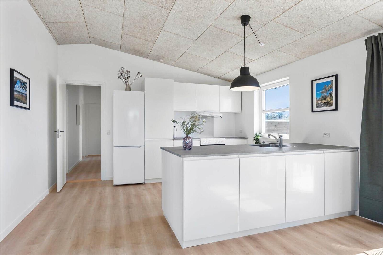 Kitchen with white cabinetry, dark countertop, and window with view outside.