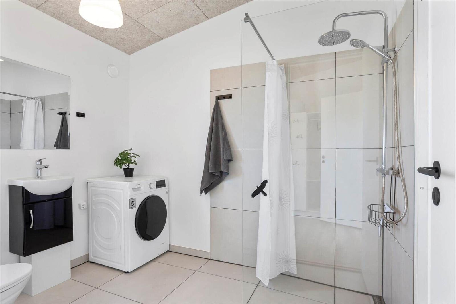 Bathroom with shower, washing machine, and mirror