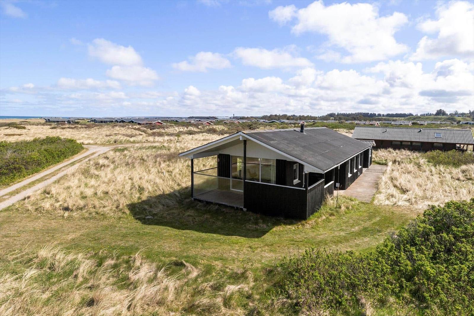 Modern holiday home with terrace in dune landscape, view of beach and sea.