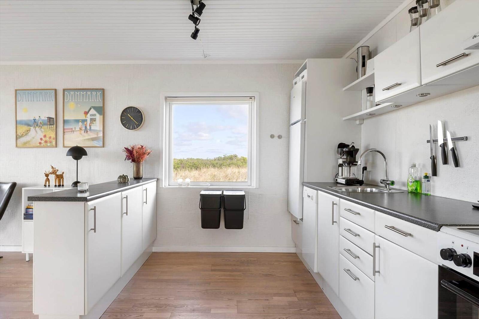 Kitchen with white built-in cabinetry, dark worktop, and window view of grassland.