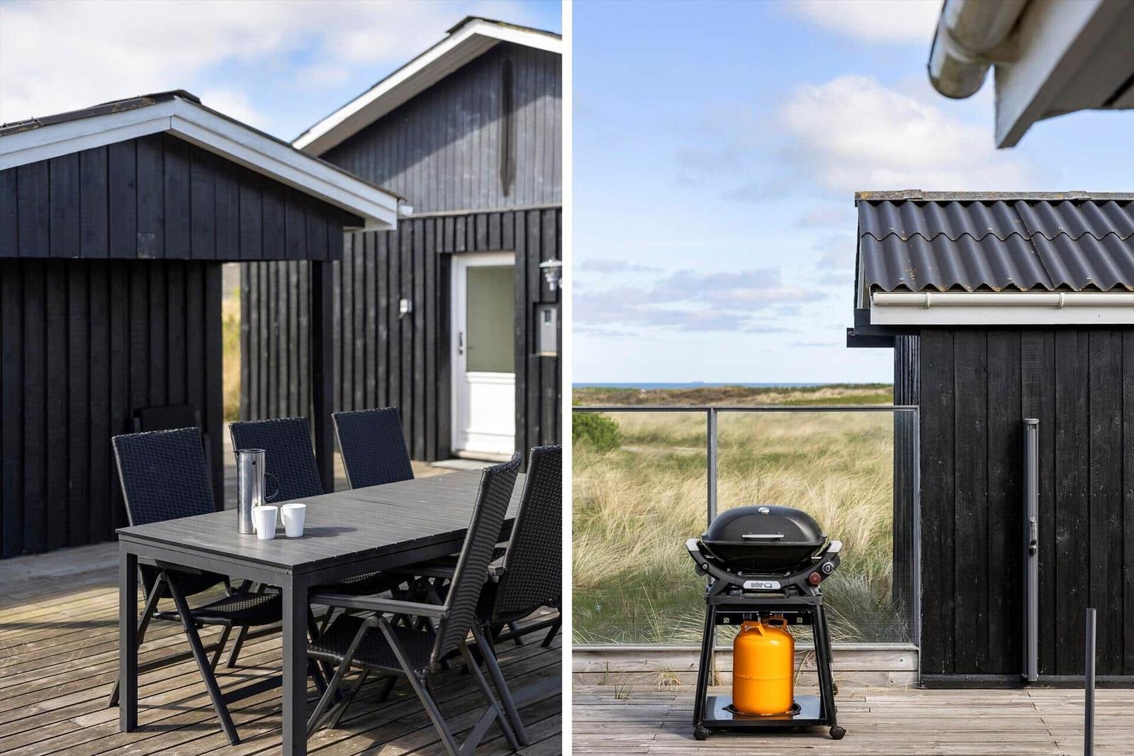 Deck with table and chairs and grill with gas canister. View of beach and grassland.