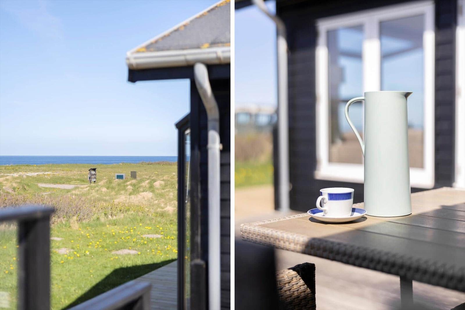 Außenbereich mit Tisch, Tasse und Karaffe. Blick auf Grasland und Meer.
