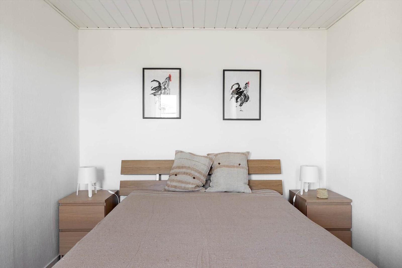 Schlafzimmer mit Bett, zwei Nachttischen und zwei Bildern an der Wand.