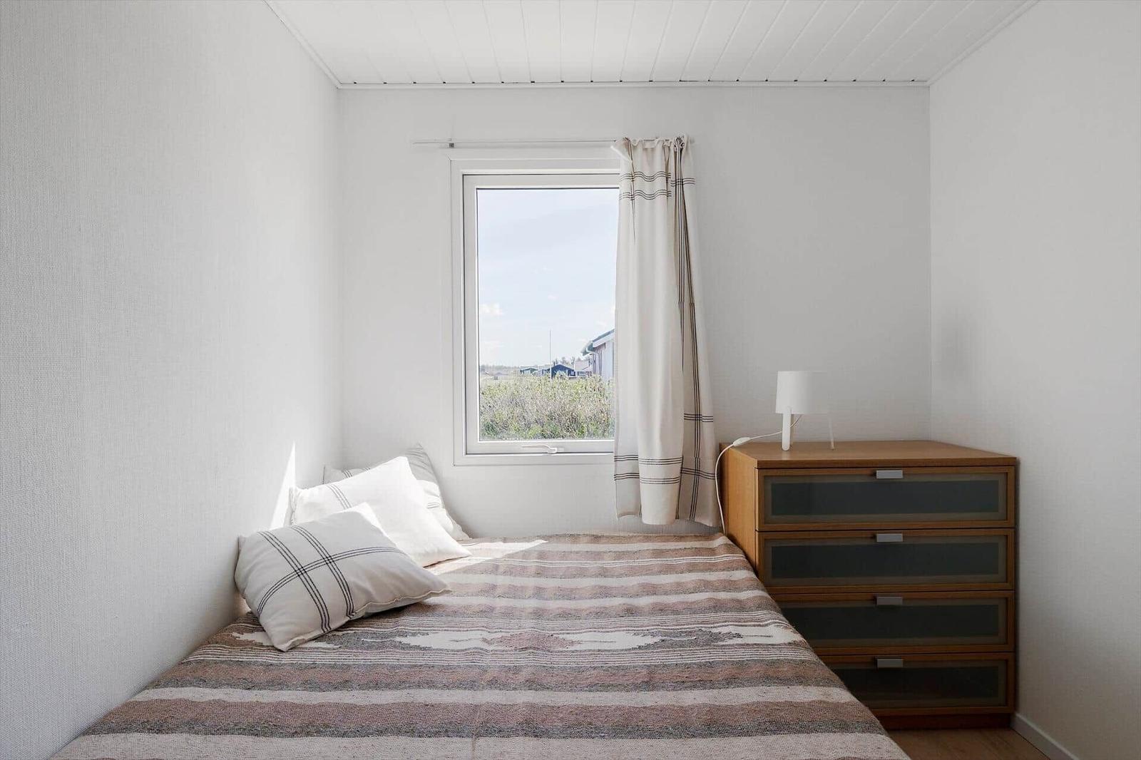 Ein Schlafzimmer mit Bett, Schrank und Fenster mit Blick nach draußen.