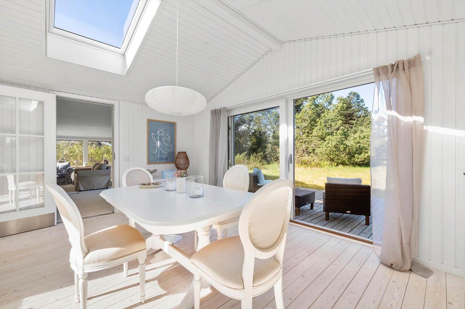 Dining room with white table and chairs, large windows, and view of terrace.