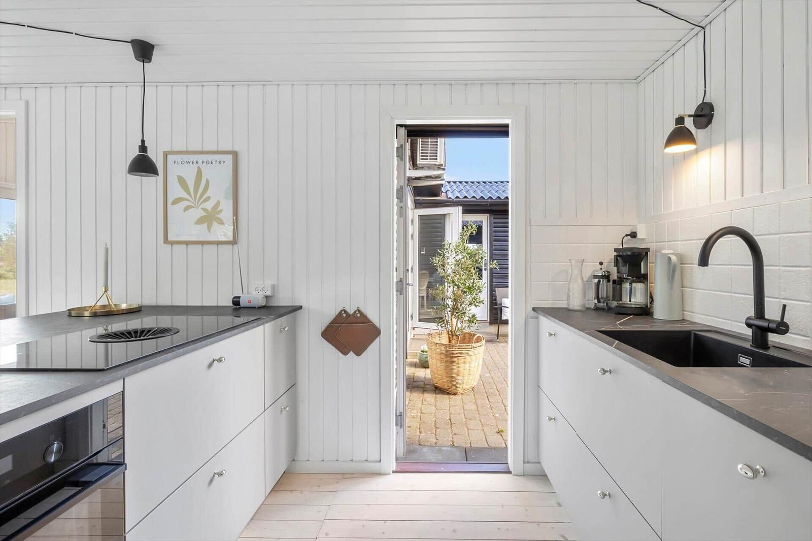 Kitchen with white cabinets, dark countertop, and view to the courtyard.