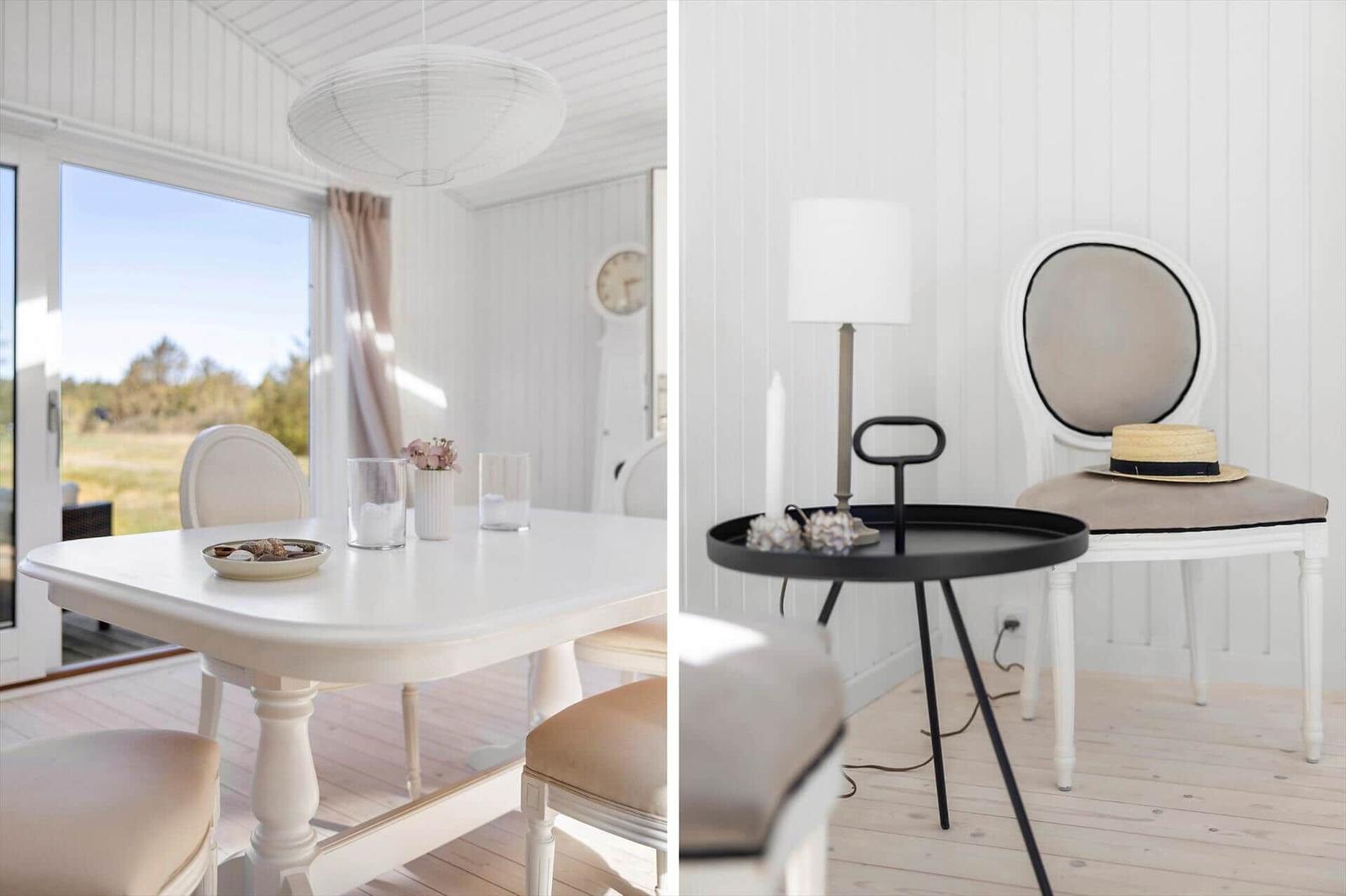 Dining room with white table and chairs, view of garden. Adjacent room with chair, table, and lamps.