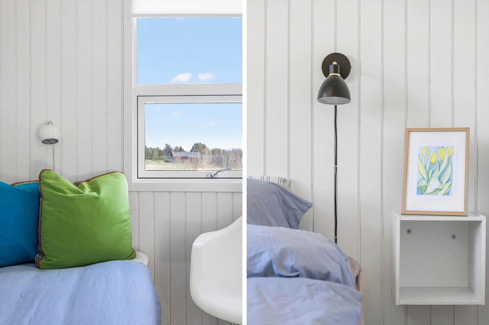 Room with window, bed, and wall lamp. A picture hangs on the wall.