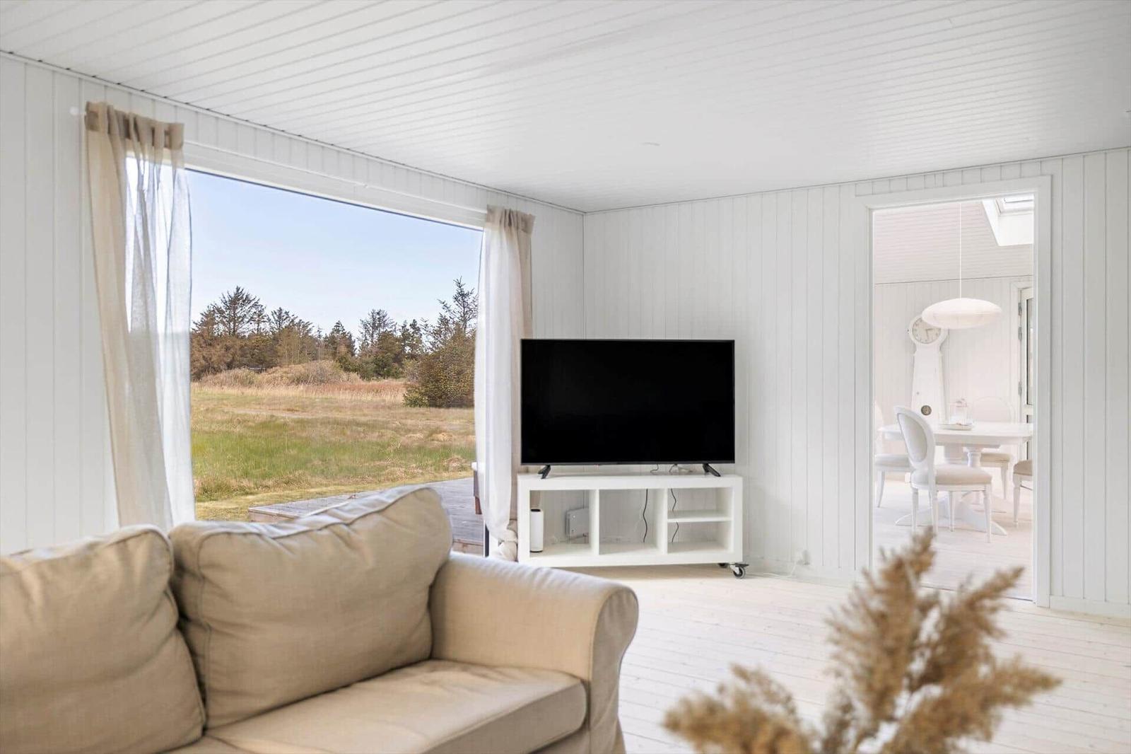 Living room with sofa, TV, and view of grassland.