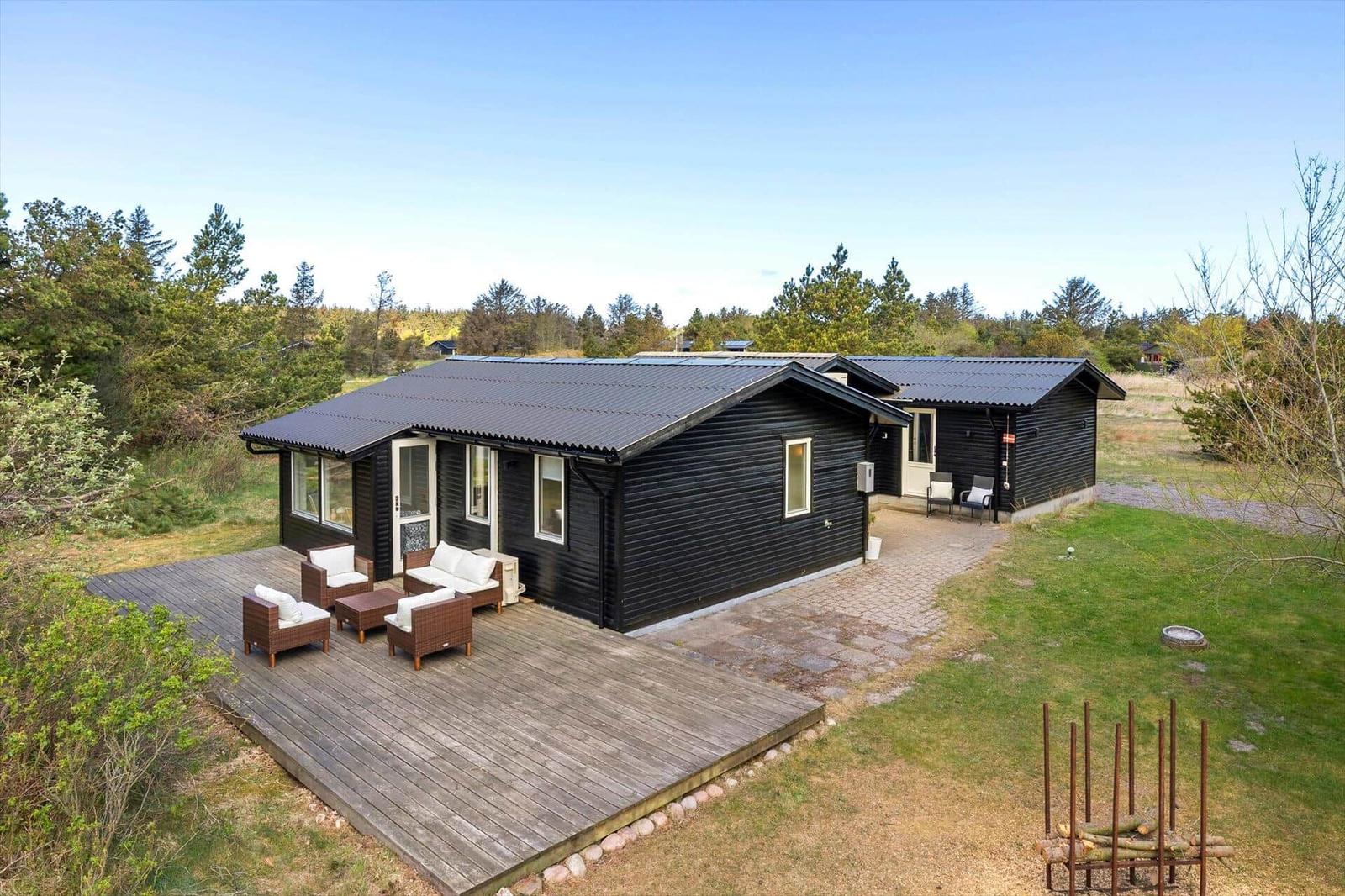 Black wooden house with terrace and garden. Furnished outdoor terrace with seating.