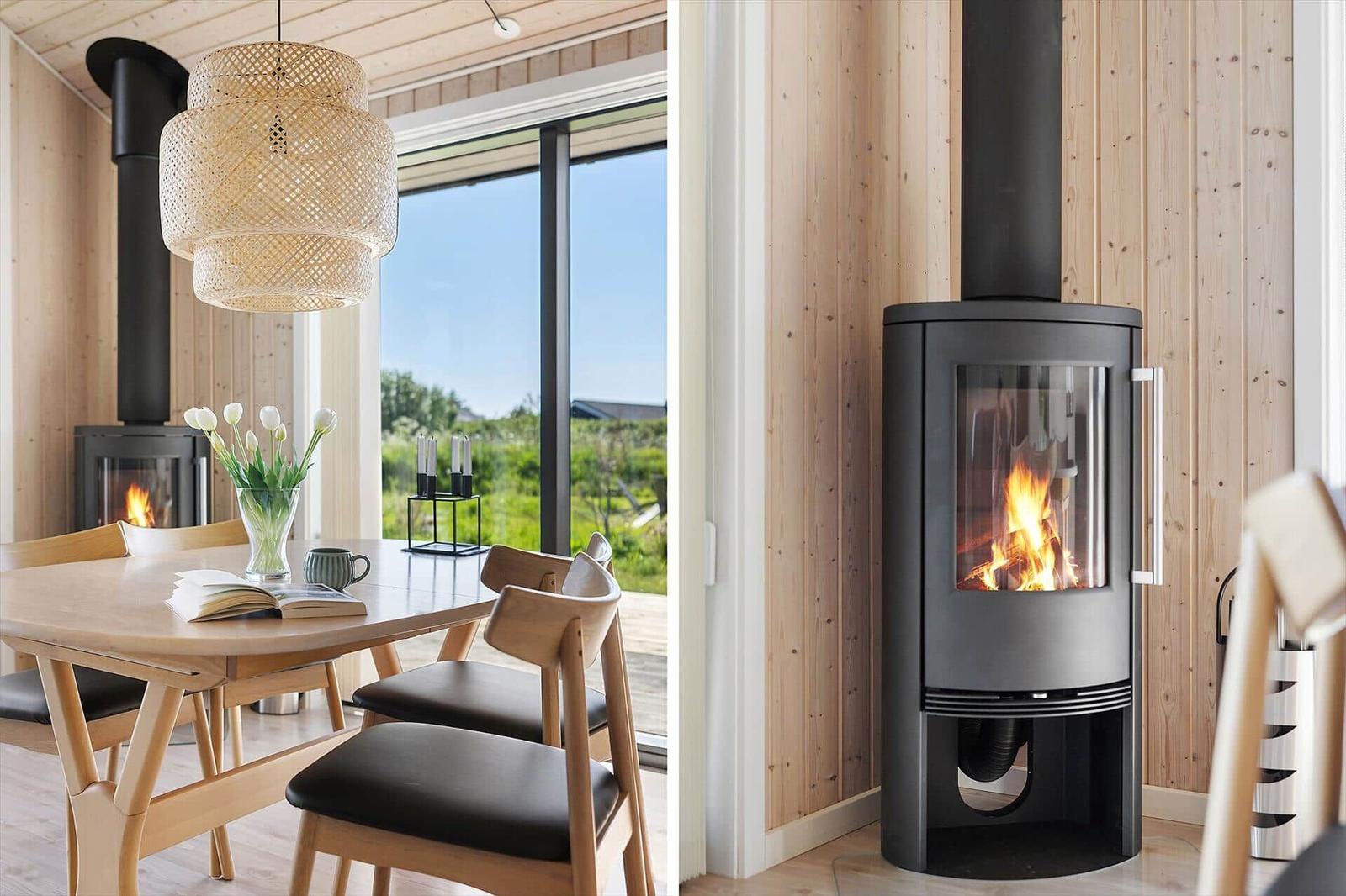 Dining table with chairs, fireplace, and window view. Wood-burning stove with fire.