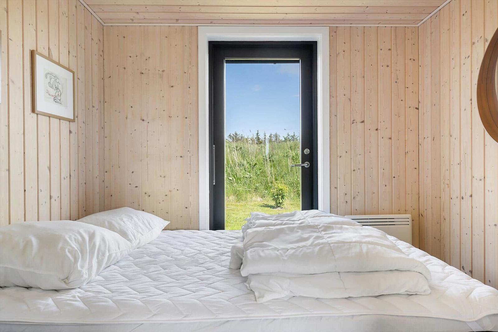 Bedroom with wooden walls and view of grassland through door