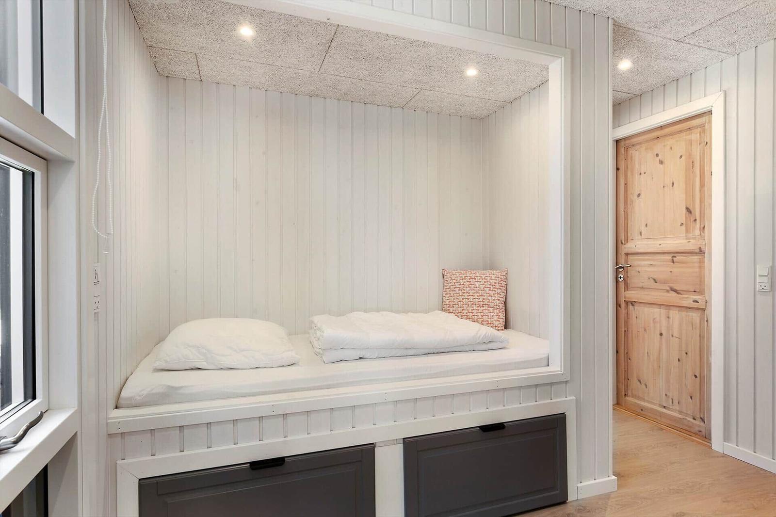 Ein Bett in einer Nische mit weißen Wänden und einem Holzschlafzimmer