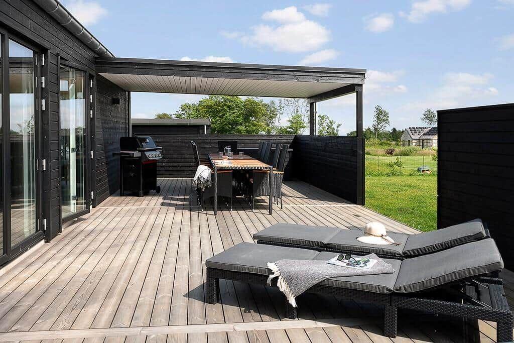 Terrasse mit Liegestühlen, Grill und Tisch unter Dach