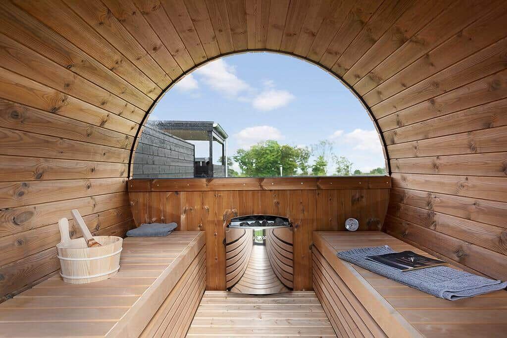 Holzsauna mit Sitzbänken und runder Aussichtöffnung nach draußen.