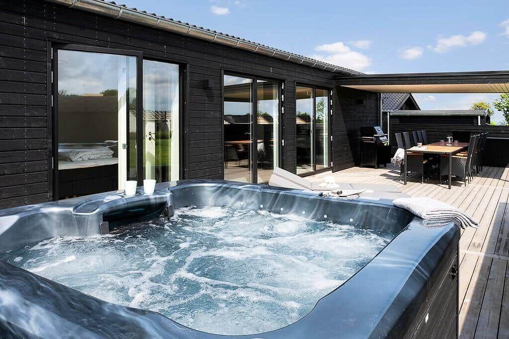 Hochwertiger Whirlpool auf Terrasse mit Blick auf modernes Haus und Essbereich.