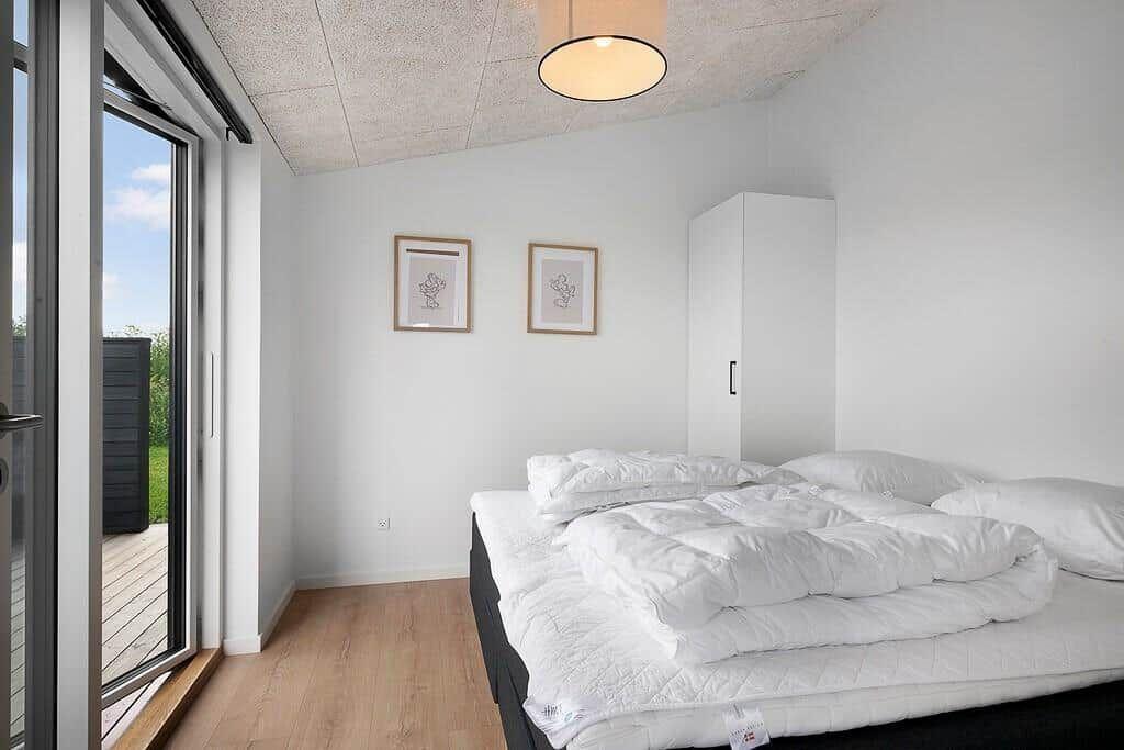 Schlafzimmer mit Bett, Schrank und Fenster zur Terrasse.