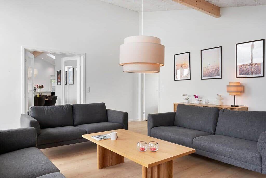 Wohnzimmer mit zwei grauen Sofas, Holztisch und Deckenleuchte.