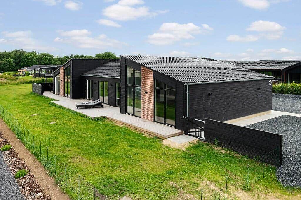 Moderne Villa mit großem Garten und Terrasse. Schwarze Fassade und Glasfronten.