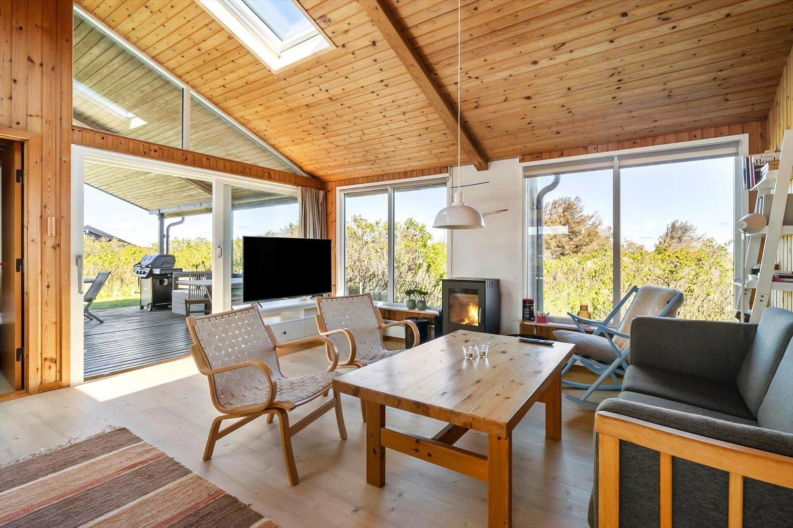 Living room with wooden ceiling, seating, and view of the garden.