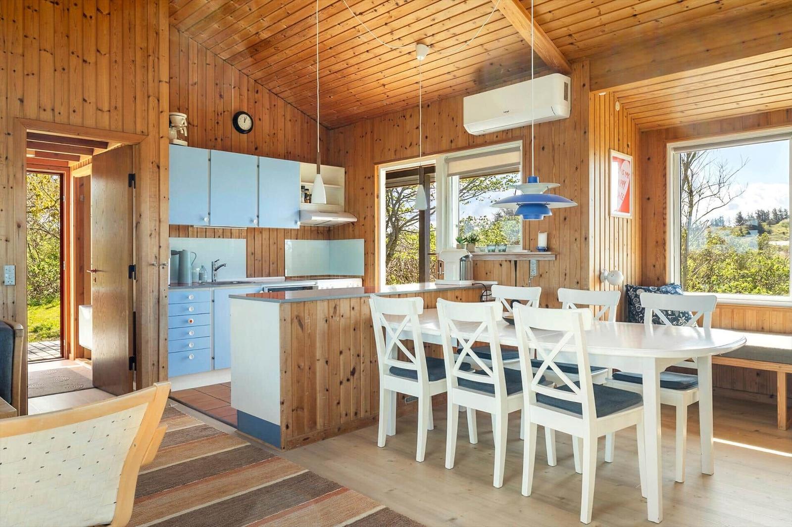 Kitchen and dining area with wooden walls, blue cabinets, and white table with chairs.