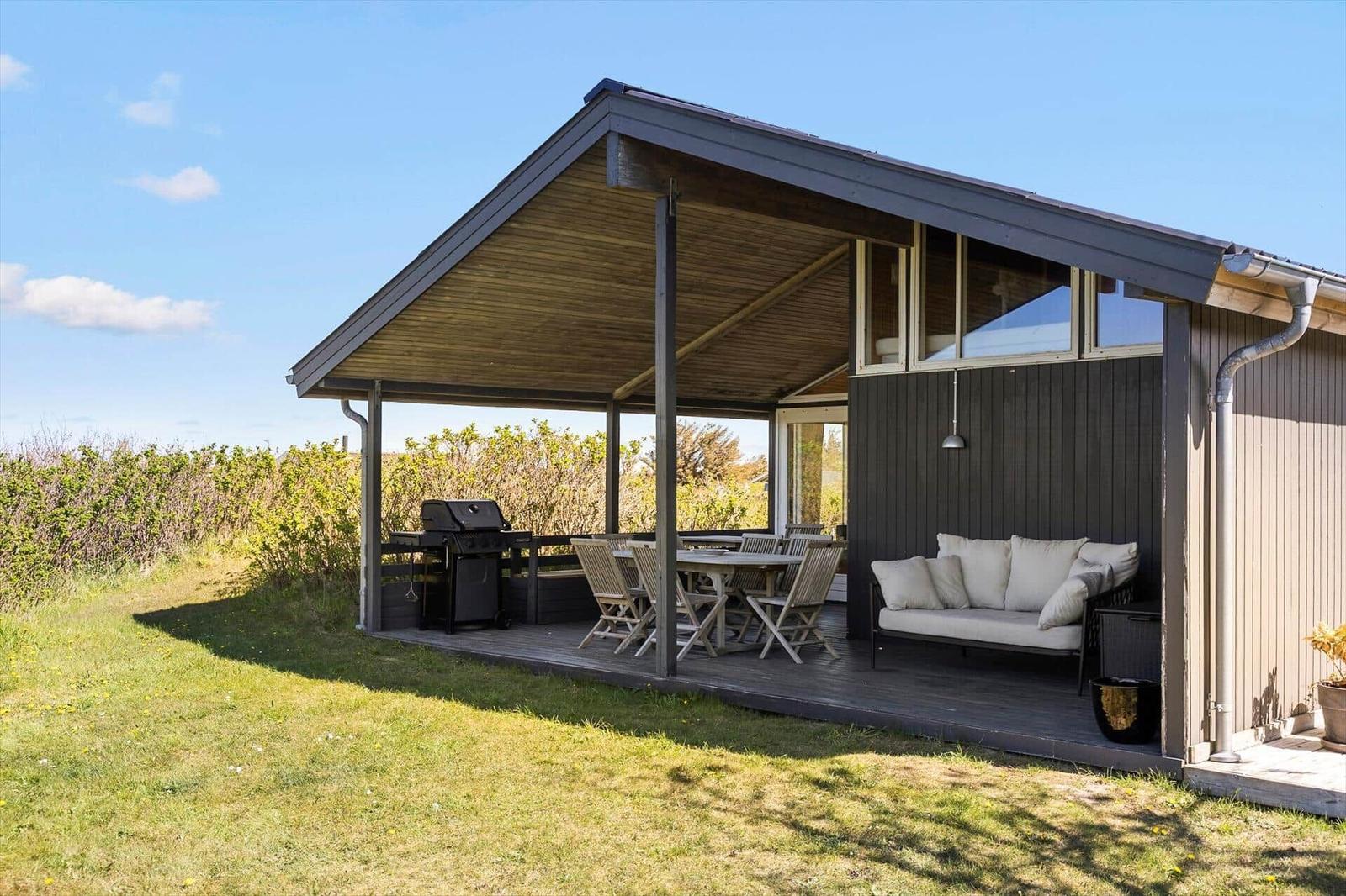 Deck with grill, table, and bench under roof