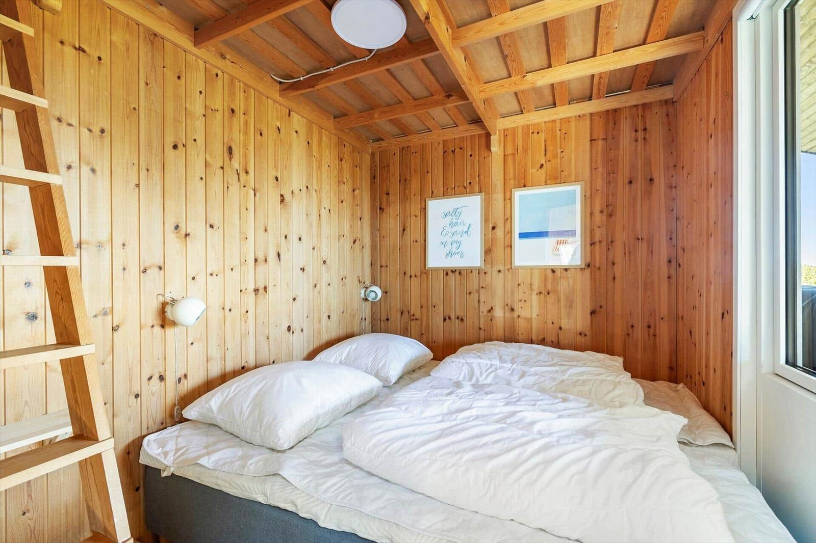 Bedroom with wooden walls, bed and ladder