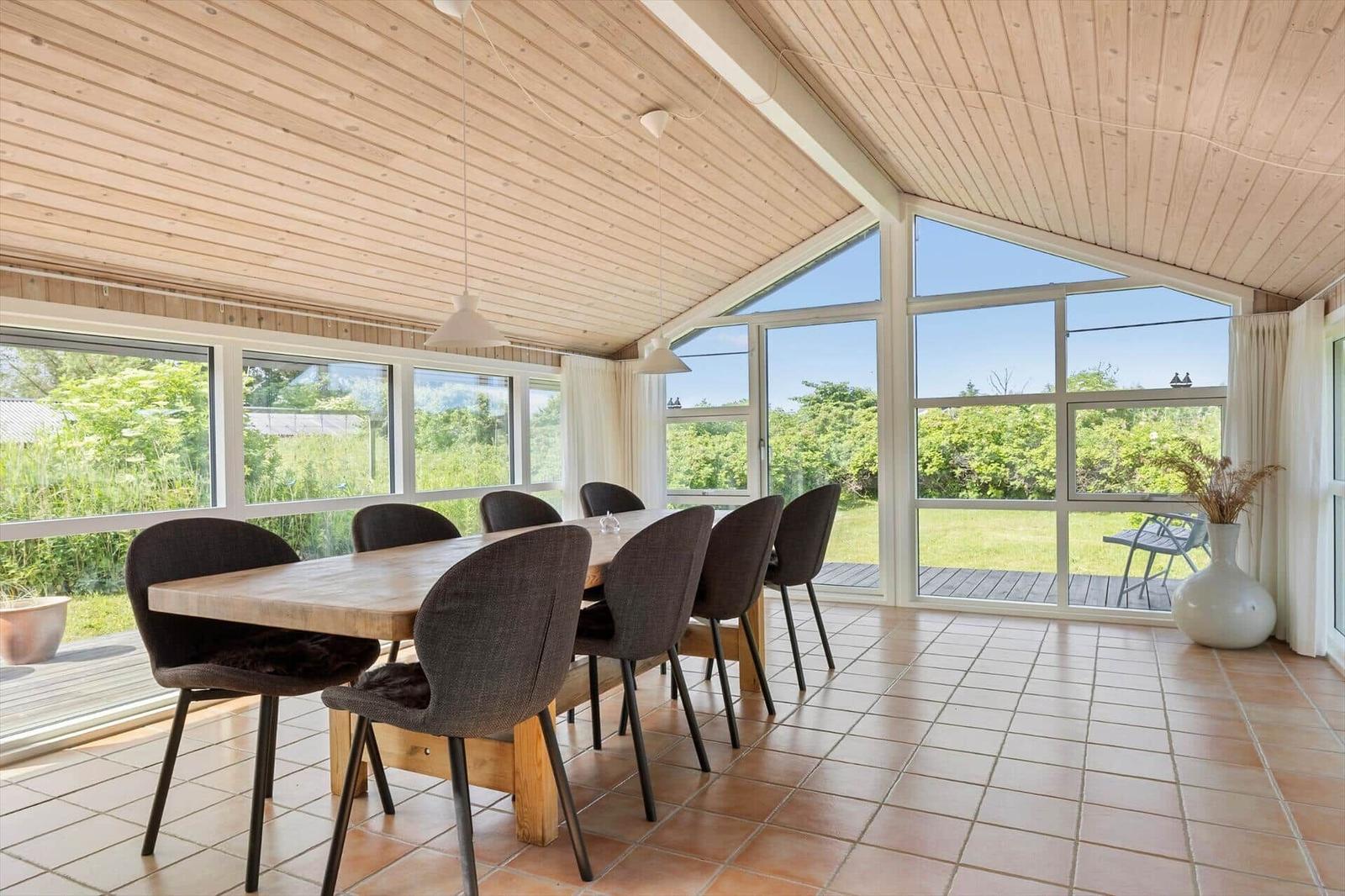 Esszimmer mit Holztisch, Stühlen und großem Fensterblick auf Garten