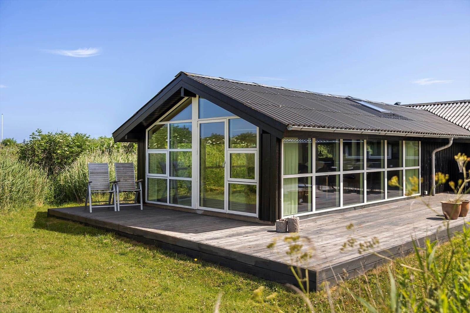 Moderne Hütte mit großem Holzdeck und Glastüren zur Außenterrasse.