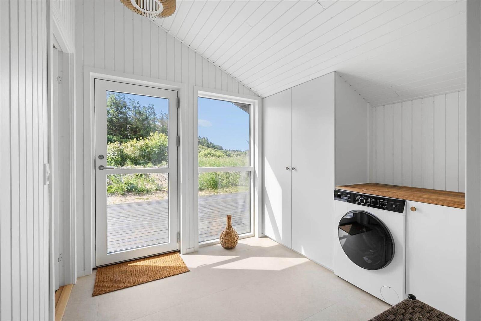 Wohnraum mit Tür und Fenster, Blick auf Grünland, Waschmaschine und Schrank.