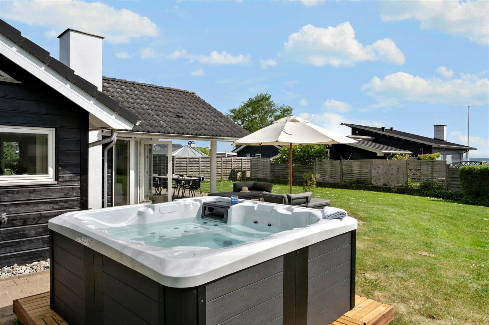 High-quality hot tub in the garden with seating and umbrella.