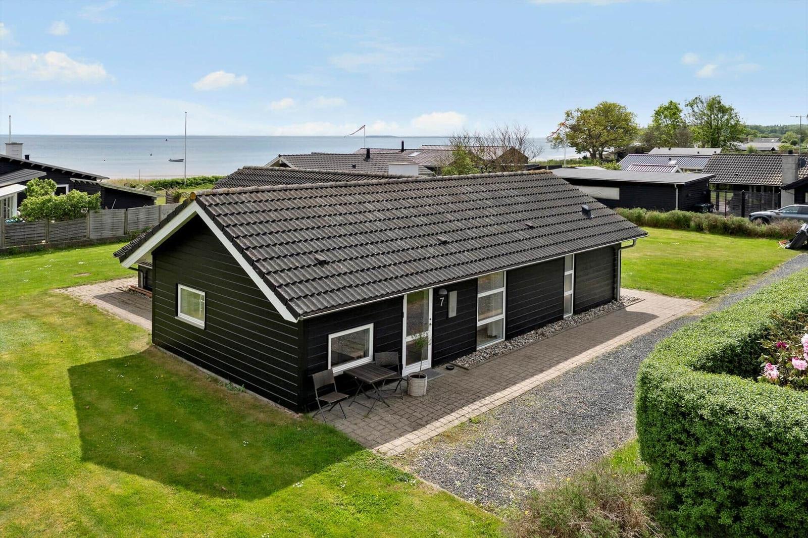 Black holiday home with terrace, garden, and sea view. Modern design with large windows.